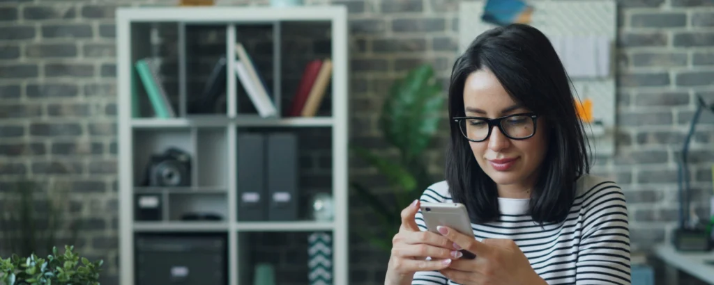 Femme qui scroll sur son téléphone pour faire un virement open banking.