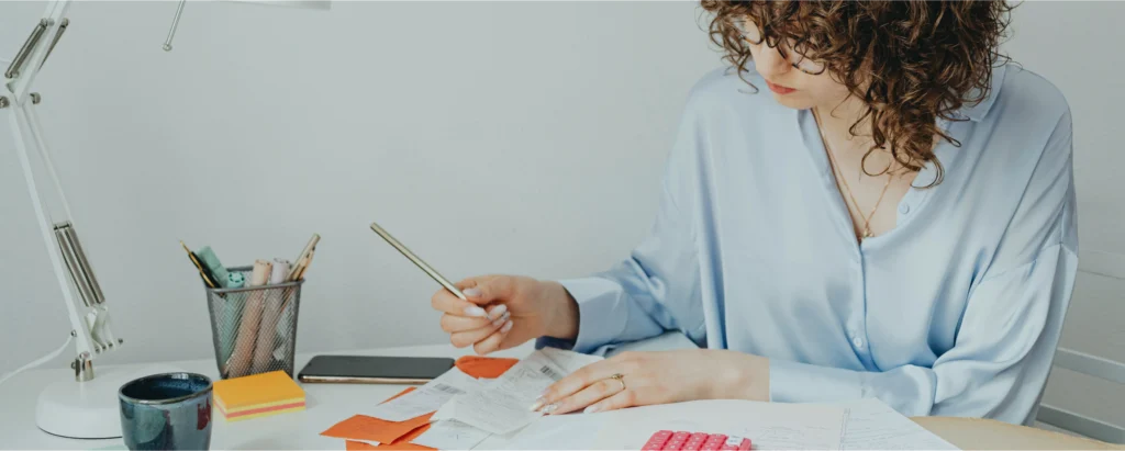 Femme qui calcule ses tickets de caisse pour éviter le découvert autorisé.