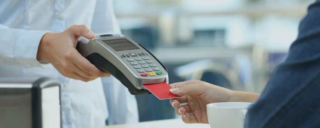Un client qui paye un marchant avec une carte bancaire dans un terminal de paiement sans se soucier de frais de carte bancaire.