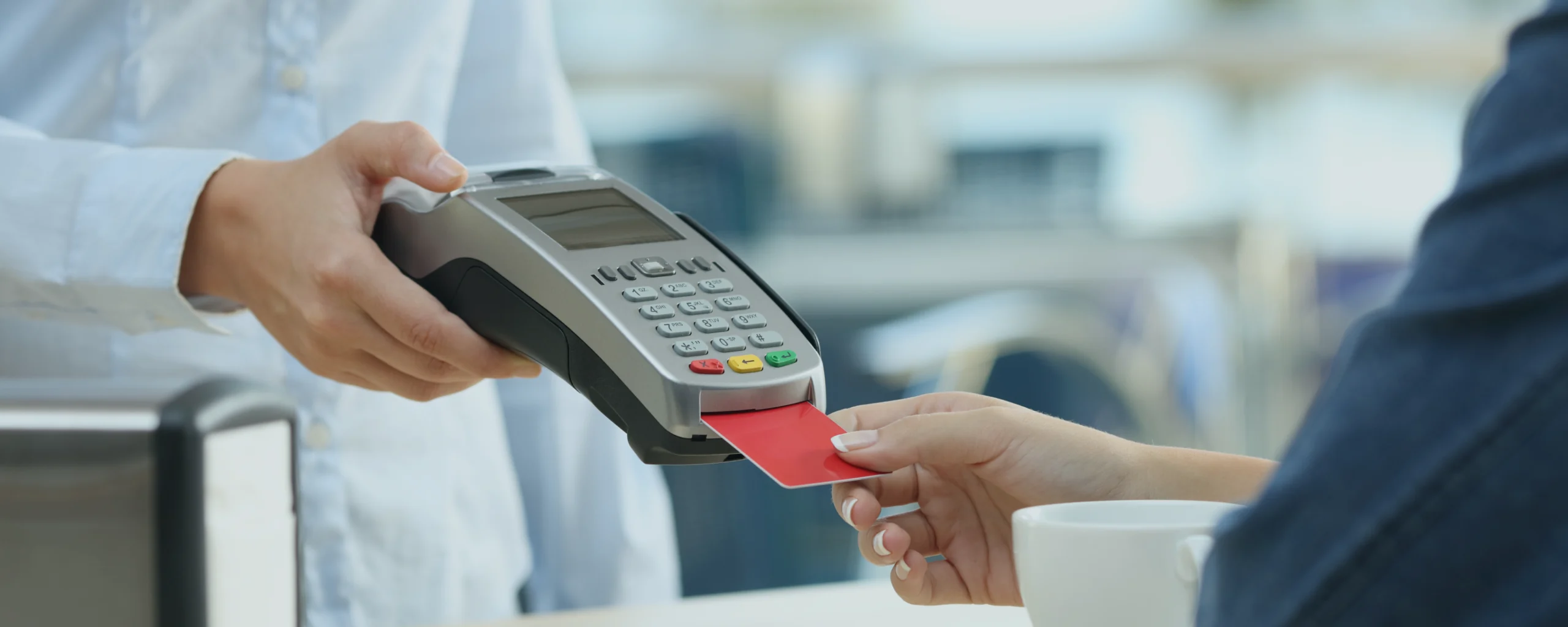 Un client qui paye un marchant avec une carte bancaire dans un terminal de paiement sans se soucier de frais de carte bancaire.