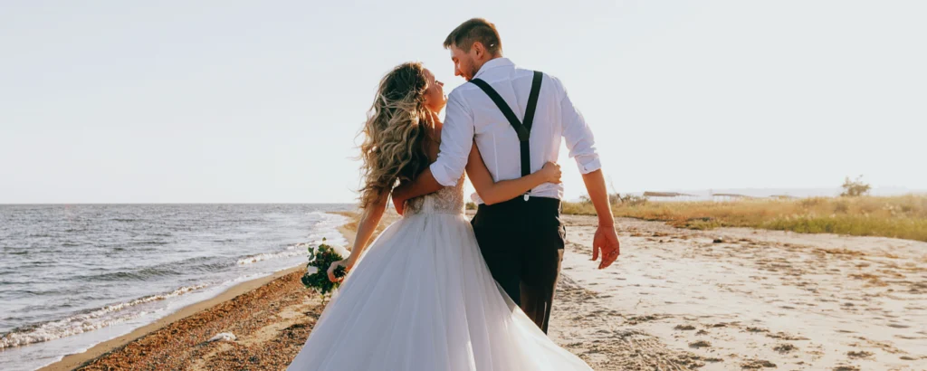 Des mariés heureux à la plage après avoir bien gérer leur budget mariage.